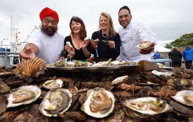 Oysters in the foreground with chefs standing behind